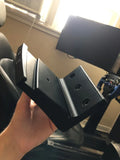 PlayStation 5 montada detrás de un monitor utilizando un soporte especializado, optimizando el espacio en un entorno de simulación de carreras.